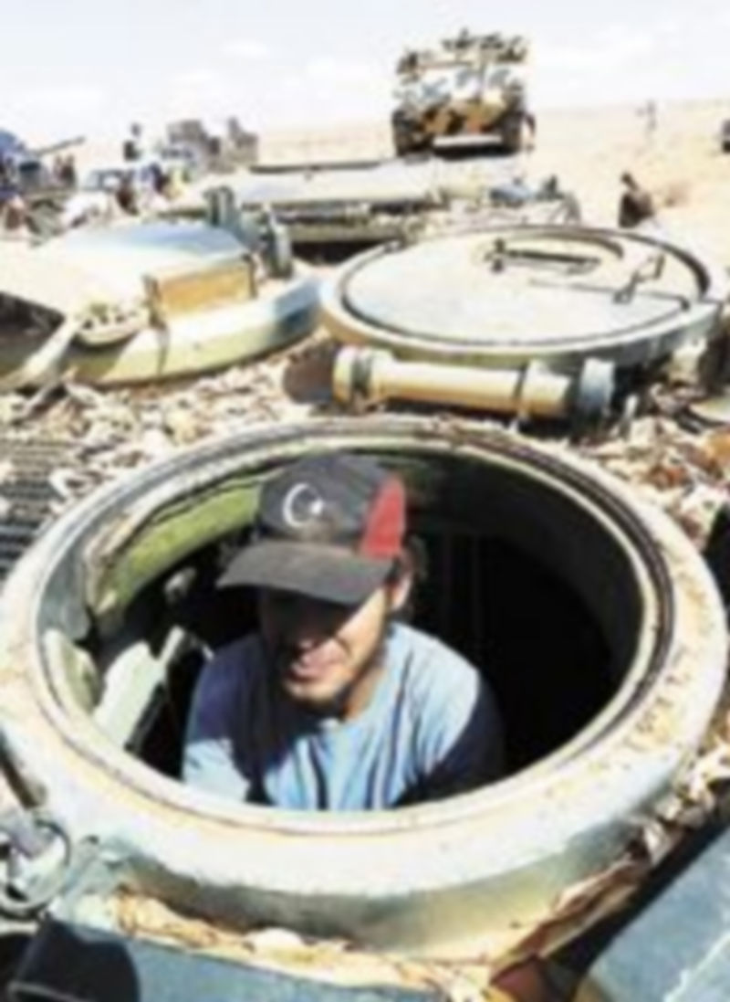 Un rebelde inspecciona un tanque  oficial encontrado en un arsenal del desierto. / Efe.