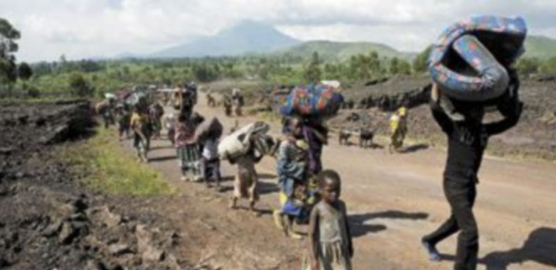 Una hilera de campesinos camina por una carretera de tierra en busca de otra ubicación en la que
