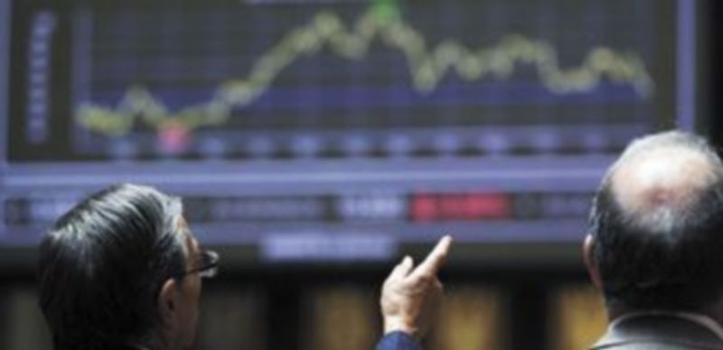 Dos inversores cambian impresiones sobre los datos que aparecen en el panel informativo de la Bolsa madrileña. / Reuters.