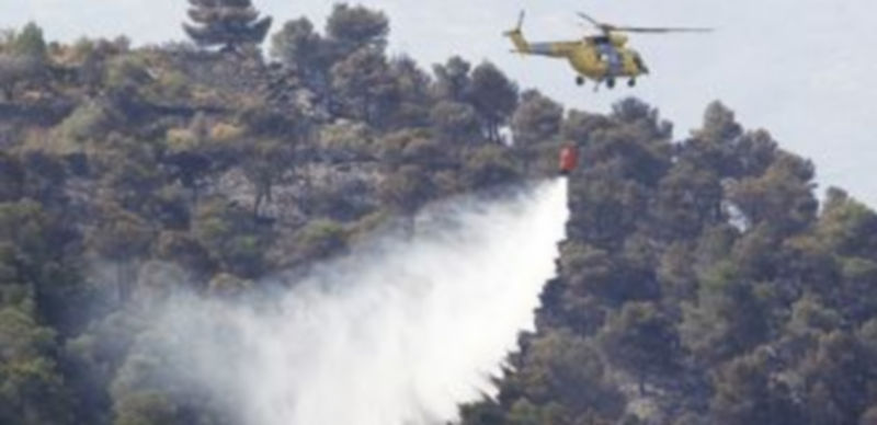 Un helicóptero encargado de las labores de extinción en uno de los fuegos de la Comunidad Valenciana. / Reuters