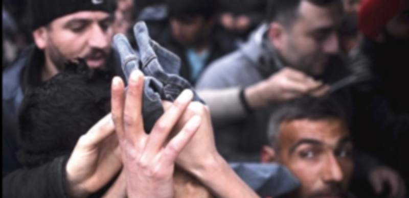 Refugiados luchan para coger ropa en el campamento provisional de Idomeni