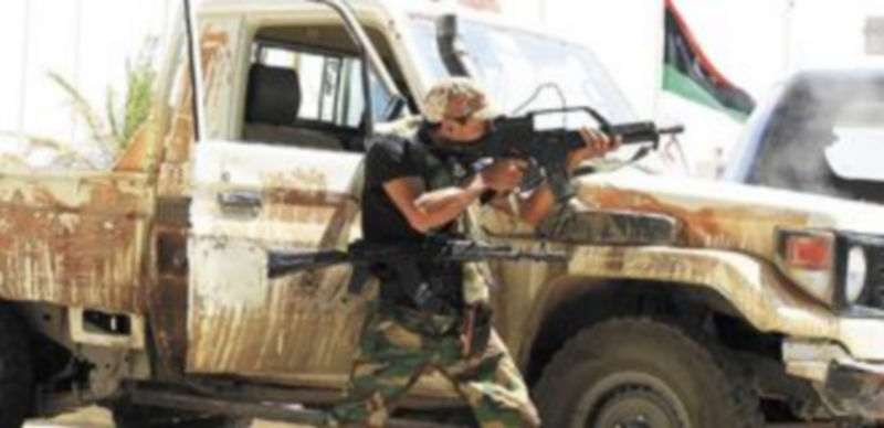 Un soldado rebelde espera la llegada de seguidores del régimen al lado de un vehículo en la base de Trípoli. / reuters