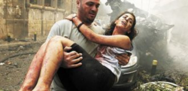 Un hombre coge en brazos a una mujer herida y la aleja de la zona más afectada por la explosión. / Reuters