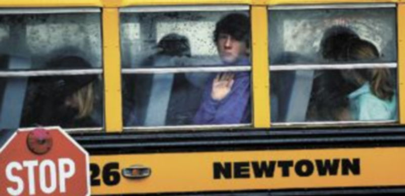 Unos niños acuden en un autobús escolar al funeral de una de las víctimas del pasado viernes en el colegio de Newtown. / Reuters