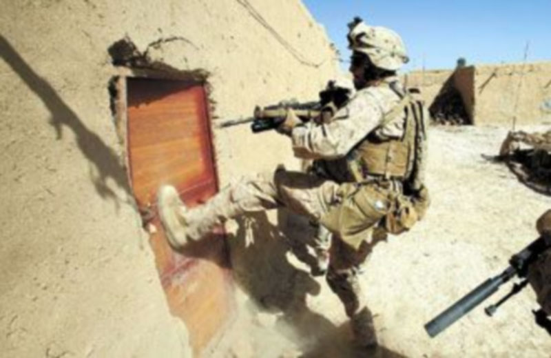 Un ‘marine’ derriba la puerta de una vivienda en la ciudad agfana de Marjah