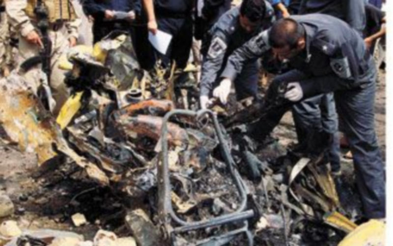 Varios policías inspeccionan los restos del coche que estalló en el barrio bagdadí de Hurriya. /REUTERS