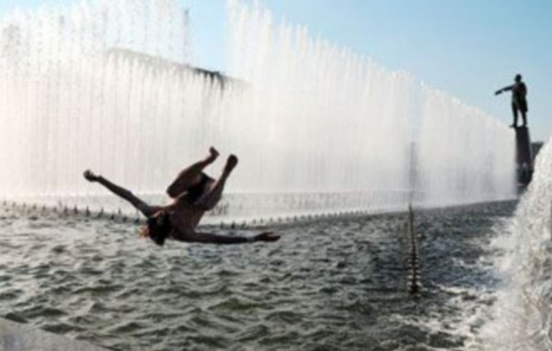 Un hombre disfruta de un baño junto a un monumento en honor a Lenín