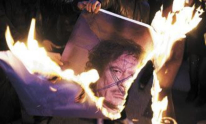 Un grupo de ciudadanos quema una fotografía de Gadafi durante una protesta organizada por Amnistía Internacional en la plaza Federal de Berna
