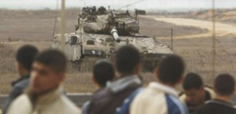 Un grupo de protestantes árabes observan la llegada de un tanque hebreo al otro lado de la frontera. / Reuters
