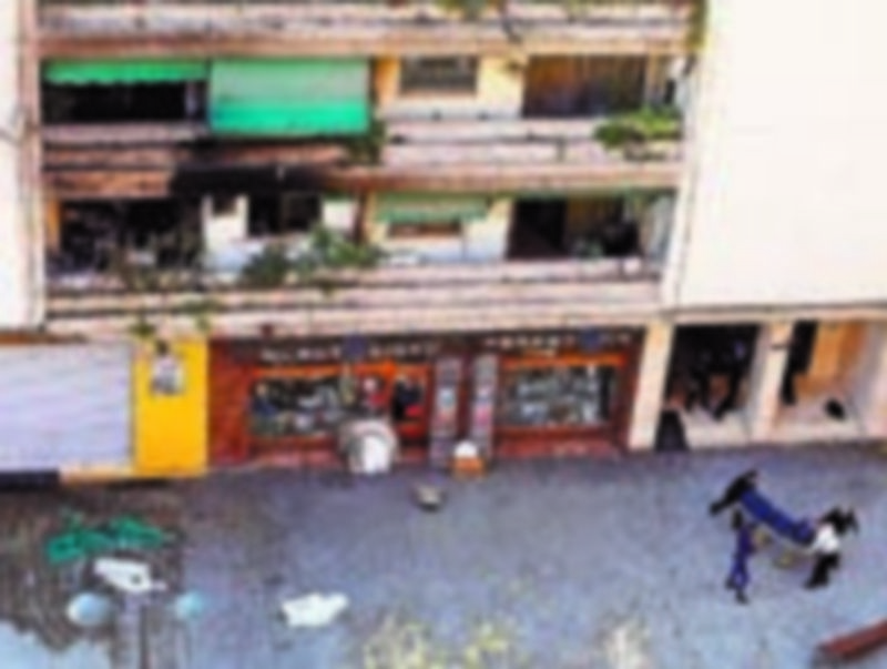 Varias personas trasladan uno de los cadáveres hallados en la vivienda de Valencia en llamas. / Efe