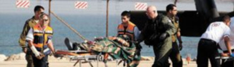 Soldados israelíes trasladan a un activista pro palestino herido durante el asalto de ayer a la Flotilla de la Libertad. / Reuters