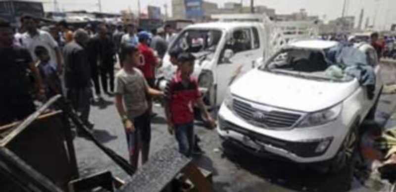 Varias personas observan el lugar donde explosionó una de las bombas que mató a 80 personas en Bagdad. / EFE