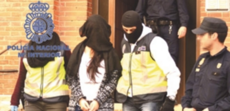 Algunos agentes de la Policía Nacional conducen a una de las presuntas yihadistas detenidas durante la operación. / Efe