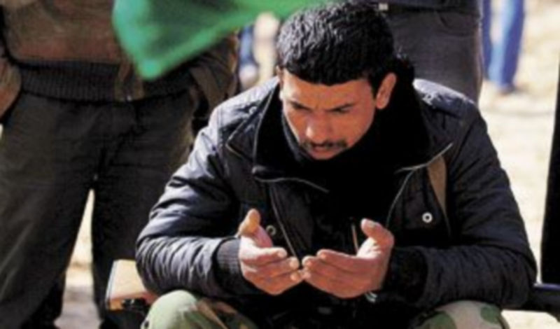 Un rebelde reza ante la tumba de una decena de compañeros muertos. / Reuters