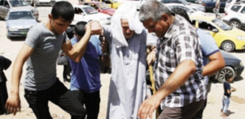 Un grupo de hombres ayuda a un anciano a subir un terraplén durante su salida de la urbe afectada. / Reuters