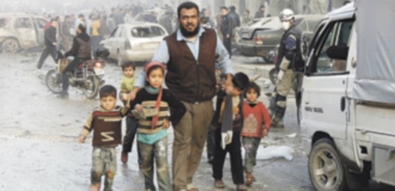 Un padre saca a sus hijos de una zona residencial de Damasco atacada por el Ejército sirio. / Reuters