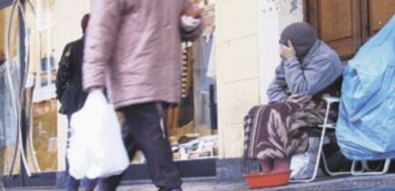 Una mujer pasa delante de un mendigo