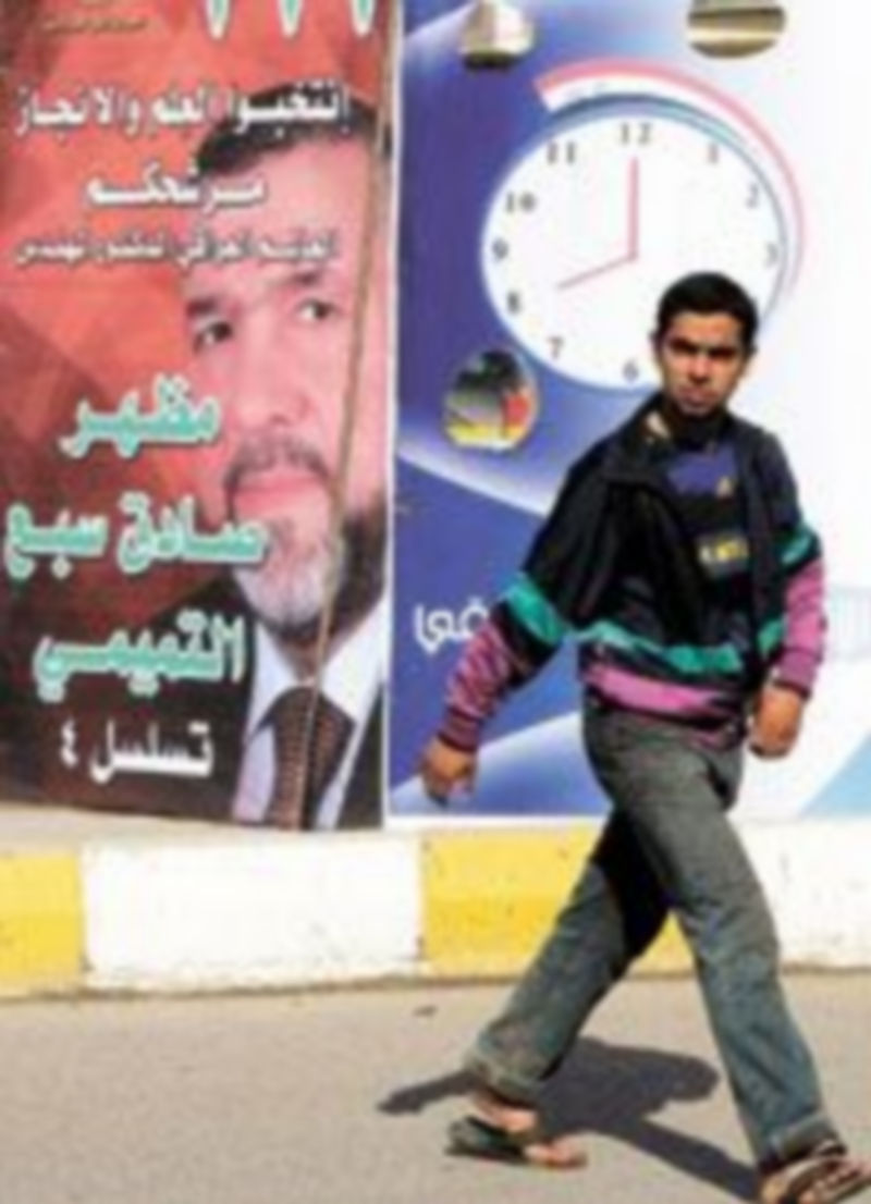 Un iraquí camina junto a un cartel de la campaña electoral de Modhir Sadi