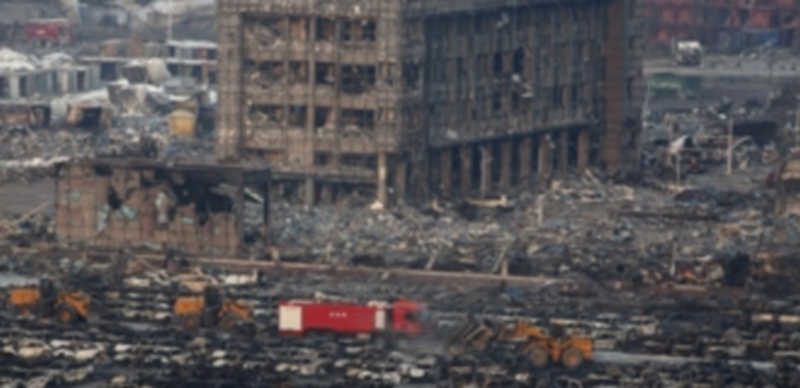 Miembros de los servicios de rescate trabajan en los vehículos y edificios quemados tras la explosión en Tianjin. / EFE