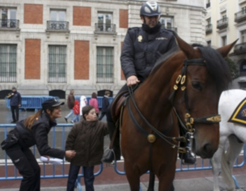 Un niño con Síndrome de Down se acerca a un caballo de la Policía nacional durante el acto celebrado en Sol. / Efe