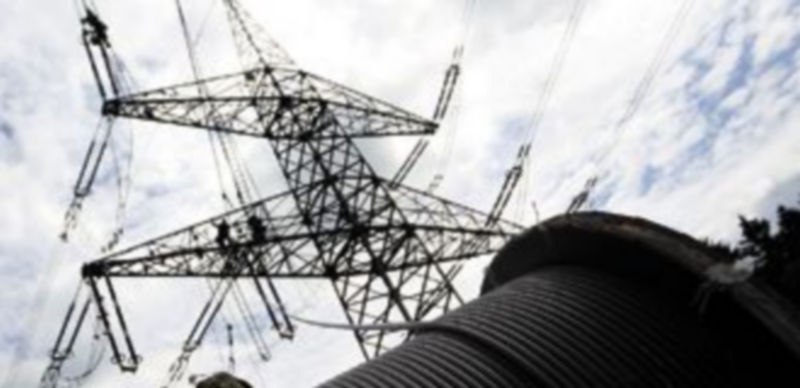Dos trabajadores tratan de arreglar los desperfectos causados por el viento en una torreta elétrica. / Reuters