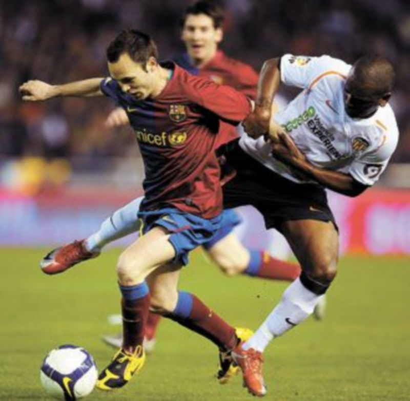 Iniesta se lleva el balón pese a la entrada de Miguel. / K.F. (Efe)