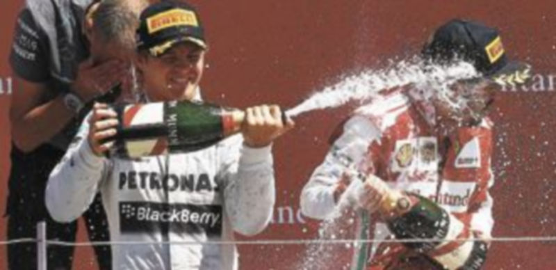 Nico Rosberg moja a Fernando Alonso con champán en el podio del circuito de Silverstone. / Reuters