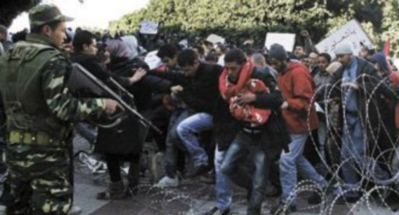 Centenares de manifestantes logran superar una barrera alambrada ante la pasividad de un soldado en la capital tunecina. / Efe