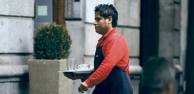 Un inmigrante que trabaja como camarero retira el servicio de una mesa de un restaurante . / Europa Press