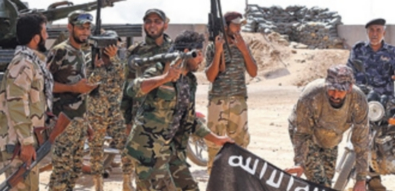 Varios componentes de  fuerzas de seguridad iraquíes sostienen armados una bandera del grupo Estado Islámico. / Efe