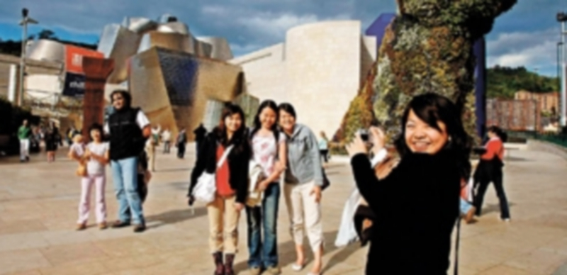 Un grupo de turistas asiáticas se fotografía delante del Museo Guggenheim de Bilbao