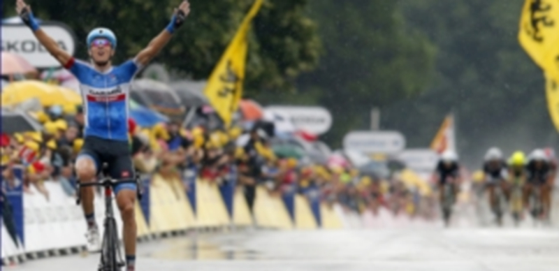 El ciclista lituano atraviesa la línea de meta con gesto de victoria y cansancio y al fondo