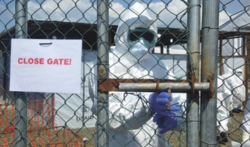 Un investigador cierra la verja del centro de tratamiento contra el ébola en Monrovia. / EFE