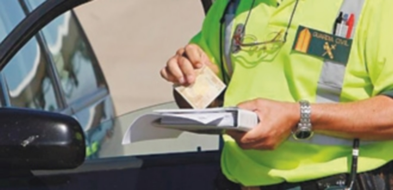 Una Guardia Civil pone una multa a un vehículo./ Efe