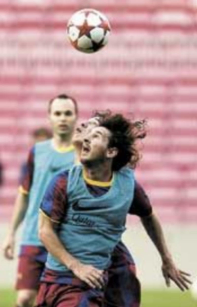 Leo Messi y Carles Puyol pugnan por un balón en la sesión de entrenamiento. / Efe.