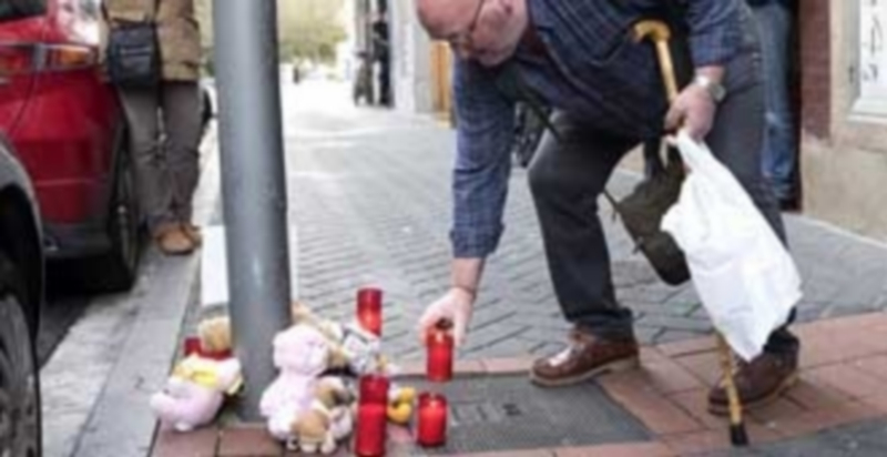 Un vecino de Vitoria deposita una vela en el ‘altar’ creado en recuerdo de la niña que fue arrojada por la ventana. / Efe