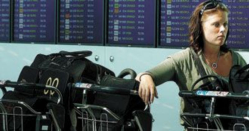 Una pasajera espera frente a un panel de información del aeropuerto de El Prat en Barcelona/ Efe