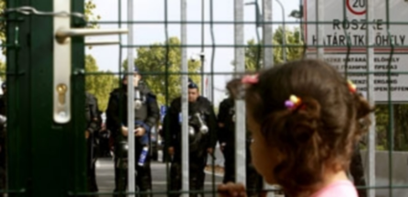 Una niña mira hacia el otro lado de la frontera invadida por la Policía. / EFE