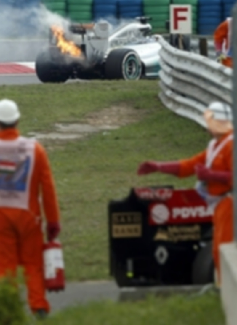 El coche de Lewis Hamilton arde ante las miradas de los operarios de pista. / Efe