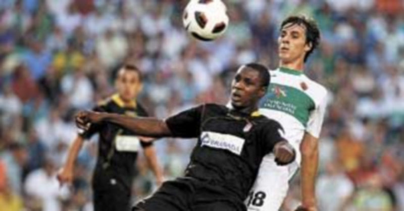 El defensa del Elche Sergio Pelegrín (d) lucha un balón con el delantero nigeriano del Granada Odion Jude Ighalo. / Efe.