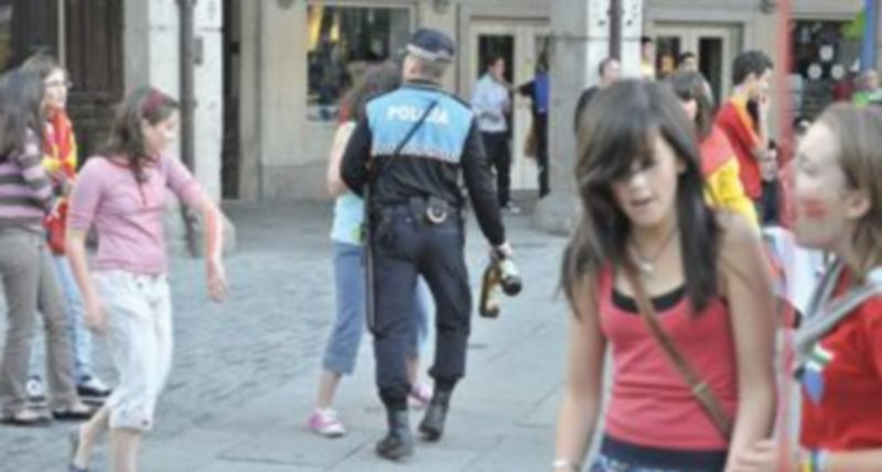 Un miembro de la policía local recoge dos botellas de vidrio durante uno de los partidos que se emitió por la pantalla gigante en la plaza Mayor./ kamarero