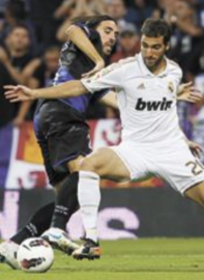 El delantero argentino del Real Madrid Higuaín (d) intenta marcharse del defensa Jordi Figueras. / J.J. Guillén (EFE)