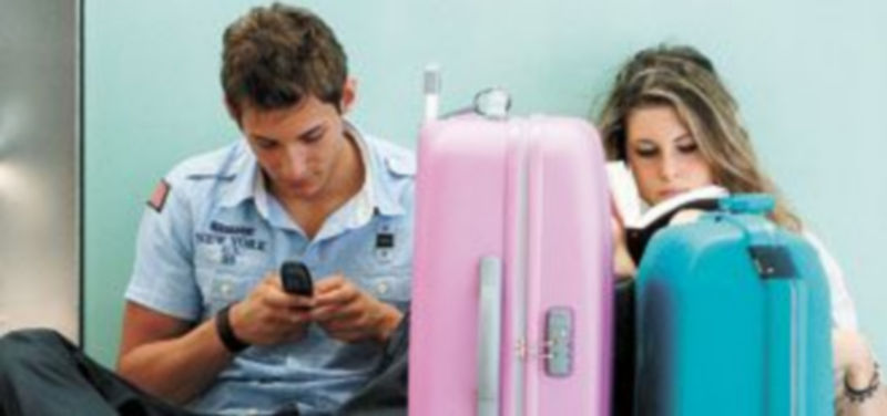 Una pareja intenta distraerse en la larga espera en la terminal catalana. / EFE