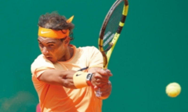 El tenista español Rafael Nadal devuelve la bola al suizo Stan Wawrinka. / EFE