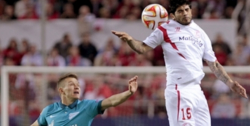 El sevillista Éver Banega salta a por el balón ante la mirada de Oleg Shatov. / EFE