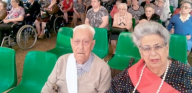 Aquilino González y Consuelo París muestran las bandas que les acreditan como rey y reina de las Fiestas de San Juan y San Pedro de la Residencia Asistida. / E.A.