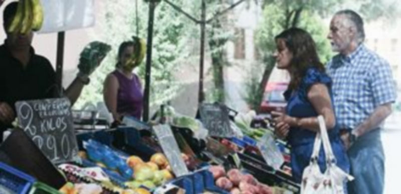 Imagen de archivo de compradores en un puesto de frutas y verduras del mercado al aire libre. / Lara Mazagatos