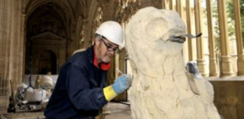 Un experto interviene sobre uno de los leones que adornan el muro perimetral./ Alberto Benavente