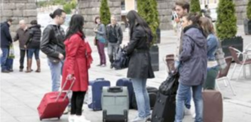 Un grupo de jóvenes turistas españoles espera con sus maletas en la zona del Azoguejo un frío día del pasado mes de junio. / Juan Martín