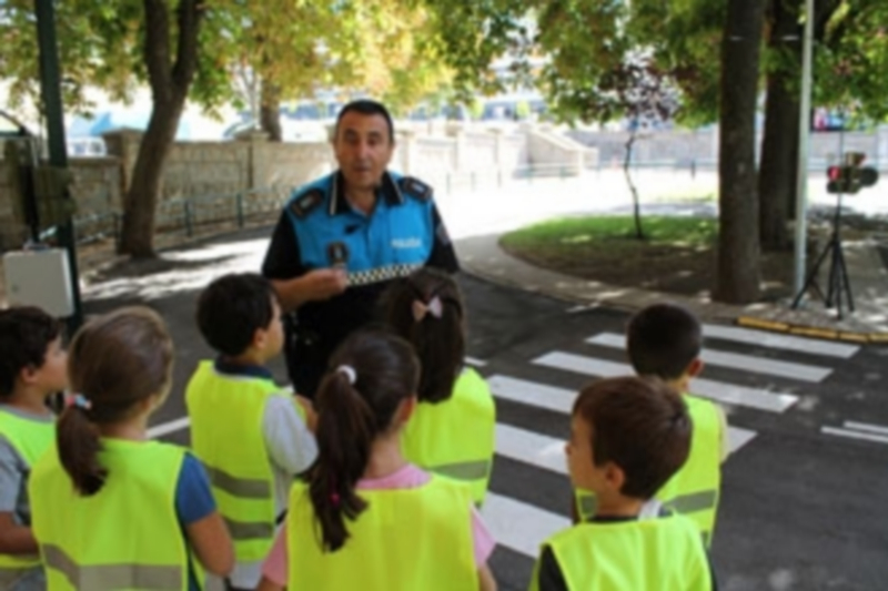 Un policía local explica a los escolares cómo tienen que cruzar por el paso de peatones